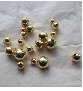 Various sizes of polished gold metal bells scattered for DIY jewelry and crafts making
