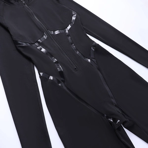 Close-up of black long sleeve jumpsuit with zipper and patent leather patchwork details