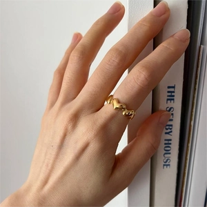 Detail of gold stacked heart ring worn on finger with minimalist lifestyle background