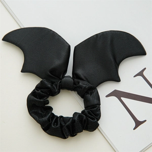 Detailed view of black satin bat wing scrunchie with pleated texture on white background