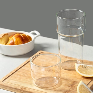 Stackable borosilicate glass coffee cups set on a wooden board with fresh lemon