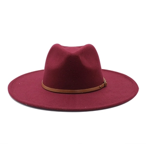Detail of burgundy fedora hat with brown leather strap and metal buckle on white background