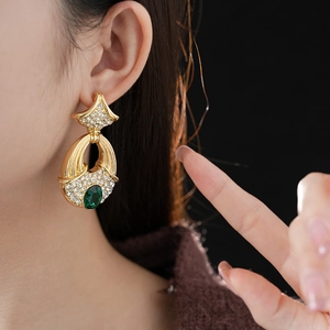 Detail of vintage gold earring with green oval gemstone and sparkling rhinestones