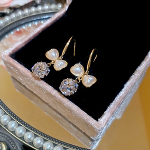 Detail of bow-shaped pearl earrings with faceted crystal pendants in a pink velvet box