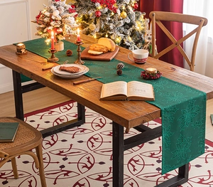 Detailed embroidery of poinsettia and holly leaves on a forest green Christmas runner