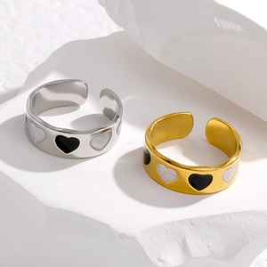 Detail view of heart-shaped enamel rings in gold and silver on white stone display