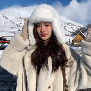 Detailed view of a white plush trapper hat with ear flaps in a snowy outdoor landscape