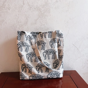 Detail shot of the metal magnetic snap button on a white canvas bag with sheep pattern