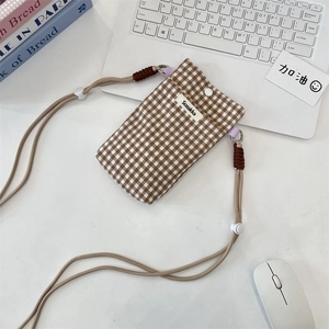 Pochette de téléphone en tissu à carreaux marron et blanc avec cordon sur un bureau épuré
