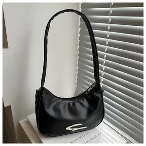 Close-up of black crescent shoulder bag with silver star metallic buckle on books
