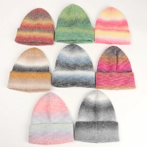 Detail view of colorful tie-dye gradient knit beanies in multiple vibrant rainbow patterns