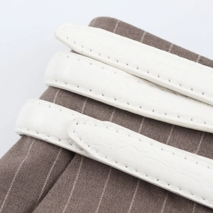 Close-up of white croc-embossed leather straps on striped suit pants fabric