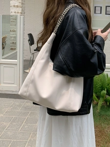 White soft PU leather tote bag with silver chain straps shown in a street style view