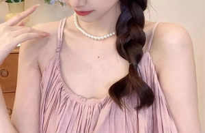 Vue détaillée d'un collier de perles élégant sur un mannequin en robe rose