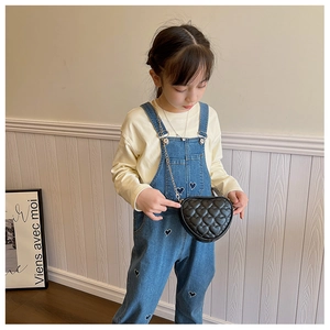 Girl wearing a black quilted heart-shaped crossbody bag with gold chain strap detail