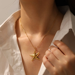 Close-up of a gold-plated starfish pendant necklace worn by a model in white