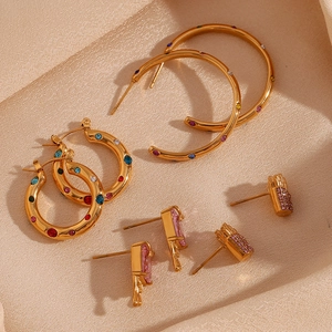 Macro shot of 18K gold earrings with colorful zircon and lava texture on silk