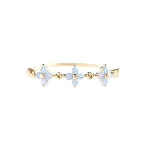 Elegant 18K gold ring featuring three light blue opal flower accents on a white background