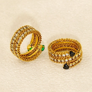 Macro shot of 18K gold spiral rings with green and black heart zircons and pavé diamonds