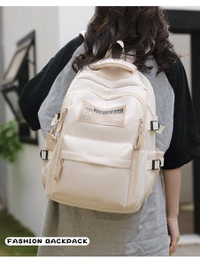 Outdoor view of a cream-colored large capacity nylon backpack with multiple pockets