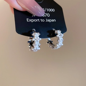 Macro shot of silver C-hoop earrings with pave-set white pearls and sparkling zircons