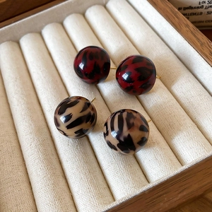 Macro shot of resin leopard print ball stud earrings in red-black and cream-coffee tones
