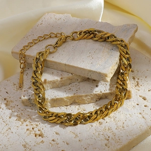 Close-up of golden Cuban chain bracelet on texture stones with silk background