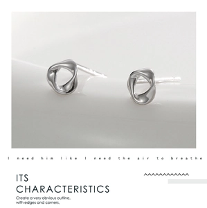 Macro shot showing the mirror-like finish and irregular geometric curve of silver stud earrings