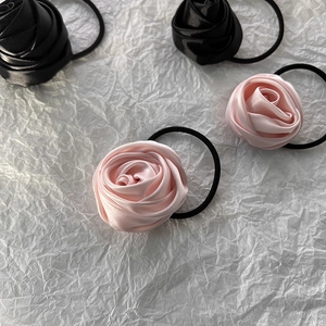 Detailed macro view of four elegant satin rose hair ties in pink and black colors