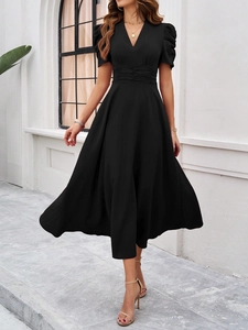 Detail of elegant V-neck black dress featuring pleated high waist and short puff sleeves