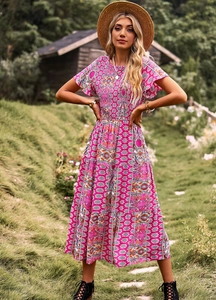Robe fleurie bohème rose avec chapeau de paille et bottes dans un cadre extérieur naturel