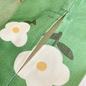 Macro detail of green daisy floral fabric car tissue holder showing texture and opening
