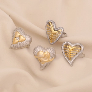 Bagues cœur bicolores argent et or avec zircons blancs sur fond de tissu beige doux