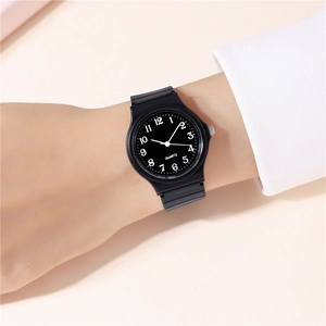 Minimalist black quartz watch with white numerals on a wrist in a clean setting