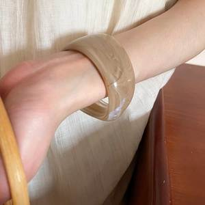 Close-up of wide marble resin bangle with elegant beige and tan irregular patterns