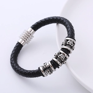 Men's black braided leather bracelet with silver skull magnetic clasp on a white plate
