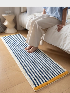 Detailed view of striped plush bedside rug with soft blue stripes and yellow edges