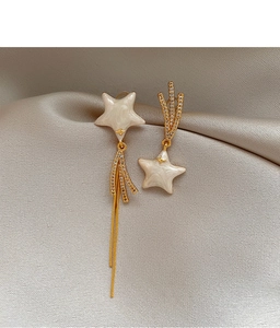 Macro detail of gold plated star tassel earrings with zircons on satin silk
