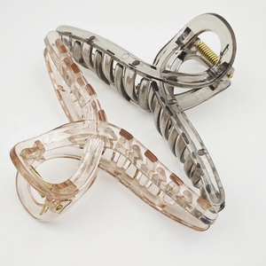 Detail of large transparent hair claws in smoky grey and amber resin with metal springs