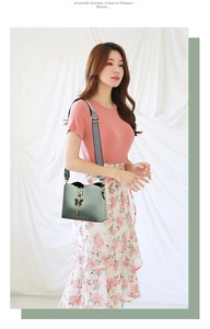 Detail of avocado green crossbody bag with black butterfly charm and wide woven strap