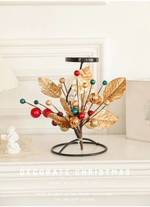 Detail view of a black metal Christmas candle holder with gold leaves and festive berries