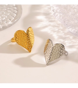 Gros plan de bagues en forme de cœur à texture martelée en finitions or et argent
