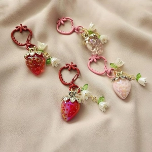 Set of four strawberry heart keychains in various pink tones with small flower charms