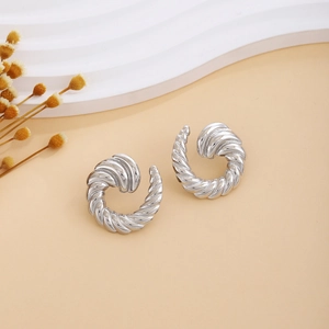 Detailed close-up of silver croissant earrings with twisted texture on warm background