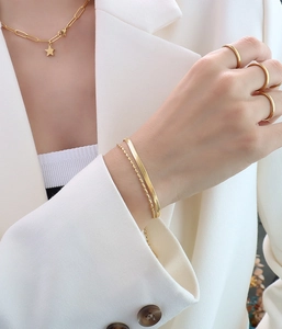 Detailansicht von mehrlagigen 18K vergoldeten Titanarmbändern und Ketten an einem Model
