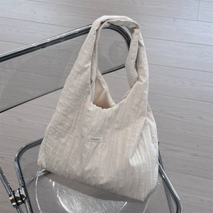 Detail of off-white pleated hobo bag with Suzakka label on soft fabric texture