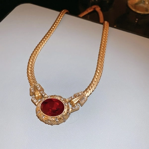 Macro shot of vintage gold serpent chain necklace with oval ruby and diamond accents