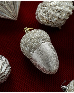 Macro di ghianda d'argento con microperle bianche su sfondo di maglia rosso natale