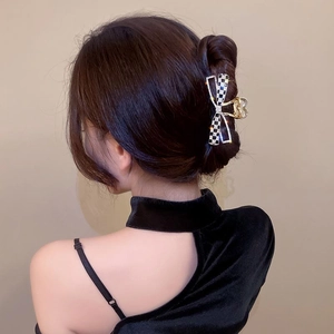 Détail d'une pince à cheveux papillon à damier avec strass portée sur les cheveux