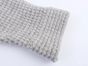 Close-up of grey knit cardigan fabric with silver shimmer and thick weave detail